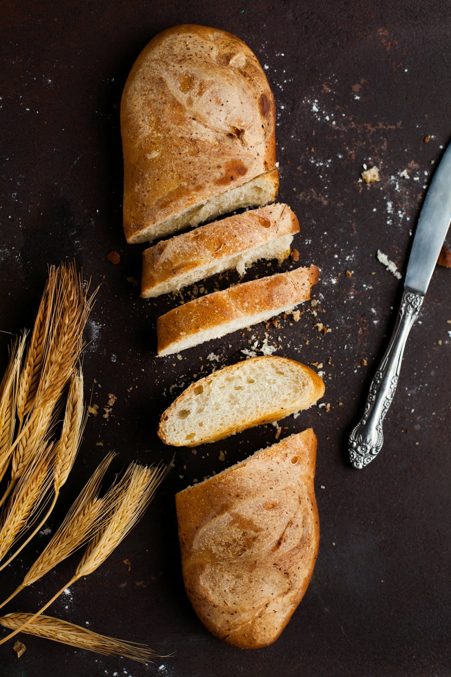 A baker scoring a sourdough loaf with a blade before baking